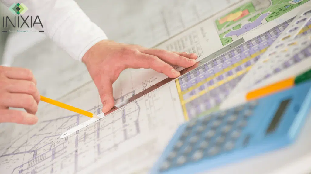 Image INIXIA - "Sur un bureau, il y a le plan d'un bâtiment et une main qui trace un trait a la règle"