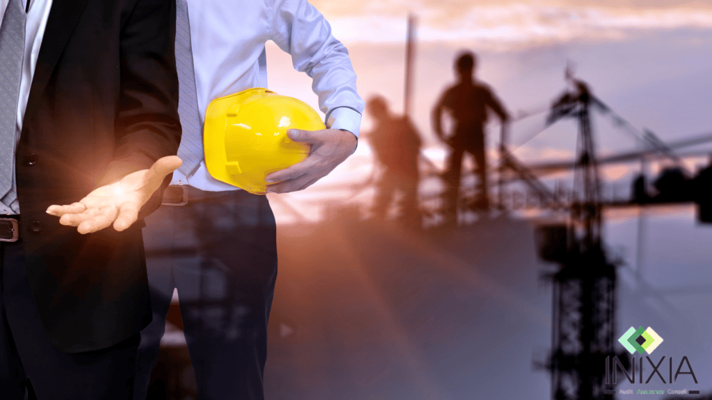 Image INIXIA - "Un homme en costard travail avec un casque de chantier devant un bâtiment de construction"