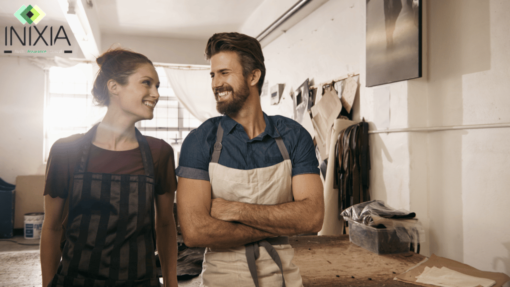 Un homme et une femme dans un atelier de maroquinerie se font un sourire.