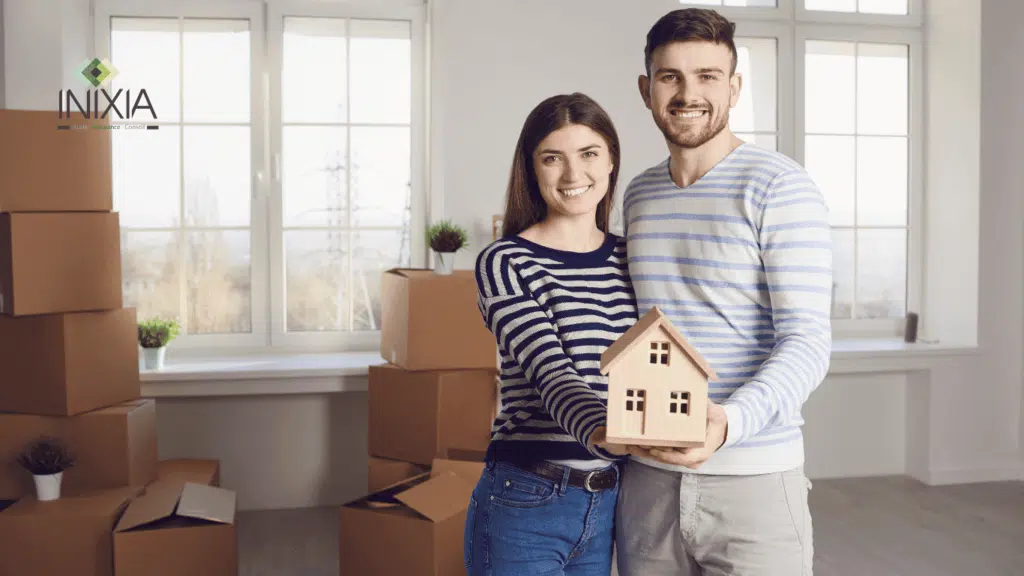 Un couple a le sourire et tient une maison dans leur main.
