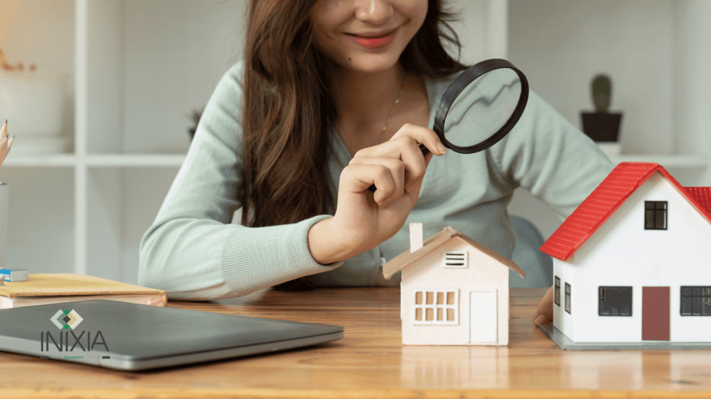 Assurance emprunteur et investissement locatif mode d’emploi - Une femme regarde une maquette de maison à la loupe
