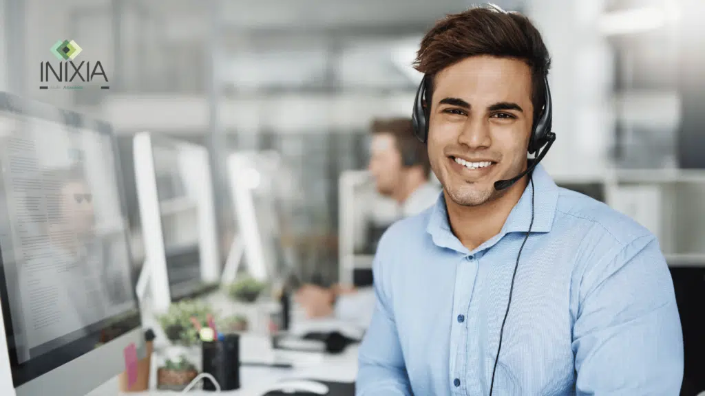 Un homme en chemise bleue avec le sourire et un casque est assis devant un ordinateur