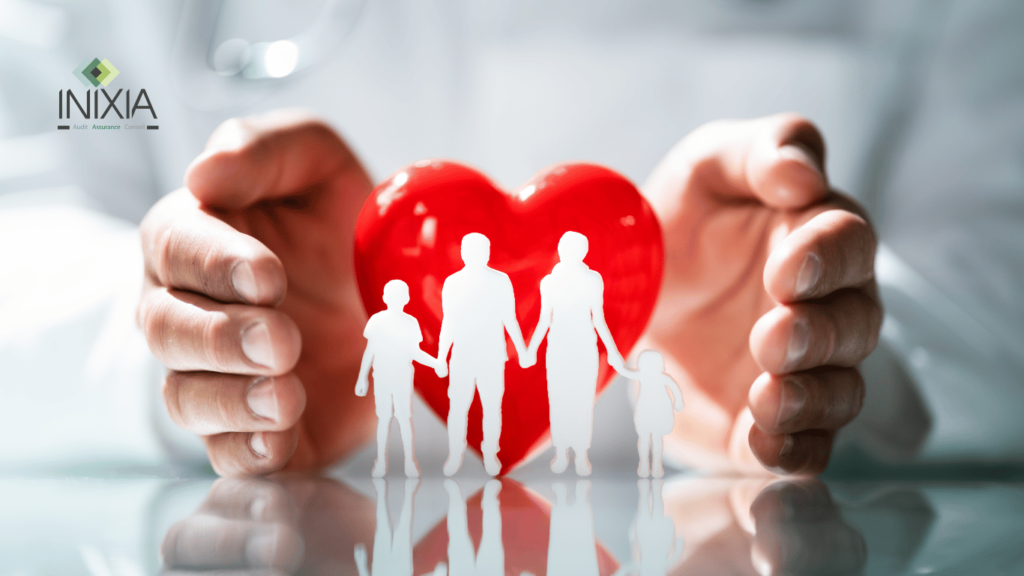 Posée sur un bureau, une petite famille façonnée en papier est placée devant un cœur rouge, tandis que des mains protectrices les encerclent