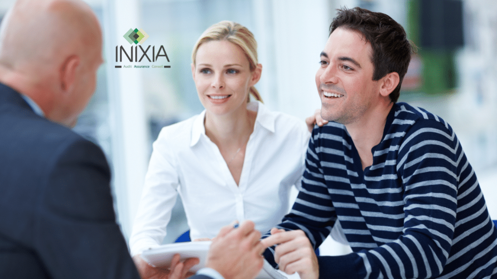 Un couple souriant discute avec un consultant en assurances de INIXIA, qui est de dos à la caméra, dans un cadre professionnel lumineux.