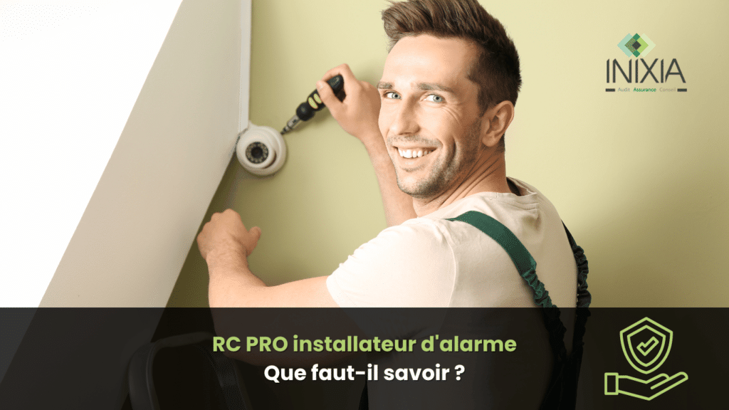 Un installateur d'alarme souriant en train de monter une caméra de sécurité sur un mur intérieur, équipé d'une perceuse. Il porte une salopette et un t-shirt, avec un logo de l'entreprise INIXIA en haut à droite.