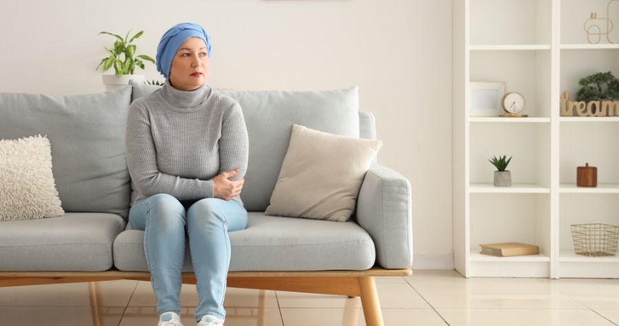 un femme atteinte d'un cancer assise sur son canapé