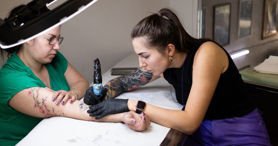 une tatoueuse en train de tatouer sa cliente